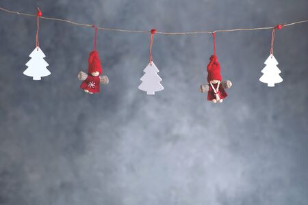 Christmas figures hanging on the rope on soft grey background.の写真素材
