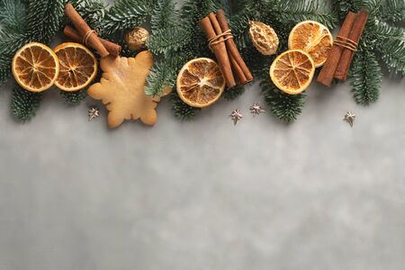 Christmas gift card with on grey background with decorated with fir, dry orange, cinnamon, gingerbread.の写真素材
