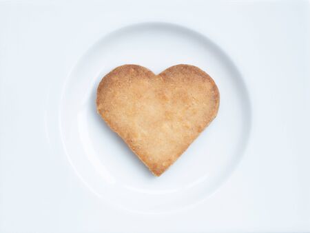 Delicious heart shaped cookie on a white plate on whitebackground.の写真素材