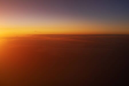 Beautiful view of sunset sky above clouds from airplane.の写真素材
