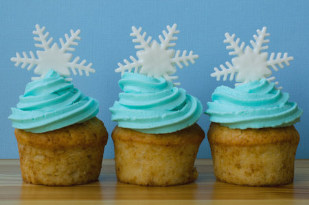 Muffin decorated with cream and snowflake . Cupcake on a blue background.Dessert for Christmas celebration. Festive greeting cardの写真素材