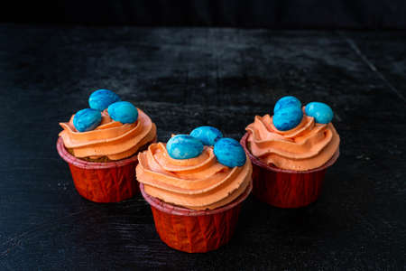 Easter cupcake with whipped orange cream. decorated with blue easter eggs. low key. Copy speceの写真素材
