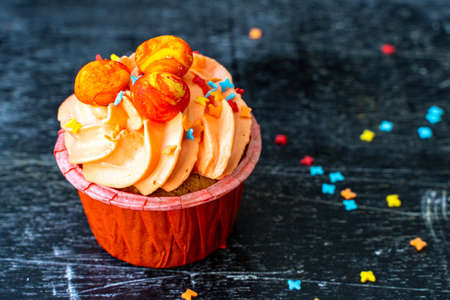 Easter cupcake with whipped orange cream. decorated with orange paint Easter eggs and pastry topping. Rustic wood backgroundの写真素材