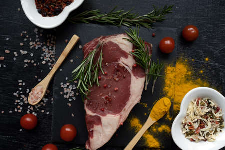 ribeye steak beef fillet chaotically decorated with sprinkled turmeric and grilled spices, spoons and heart-shaped dishes with salt and spices. Artistic messの写真素材