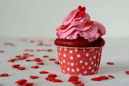 Valentines day cupcake is decorated with red hearts on white concrete. Copy space. On white...
