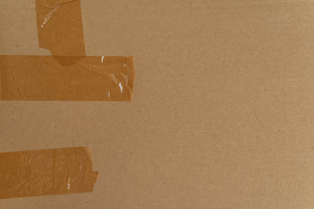 Brown cardboard with tape stripes. Abstract textured background. Moving, reclamation, poster.の写真素材