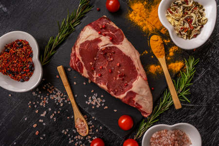 ribeye steak beef fillet chaotically decorated with sprinkled turmeric and grilled spices, spoons and heart-shaped dishes with salt and spices. Artistic messの写真素材