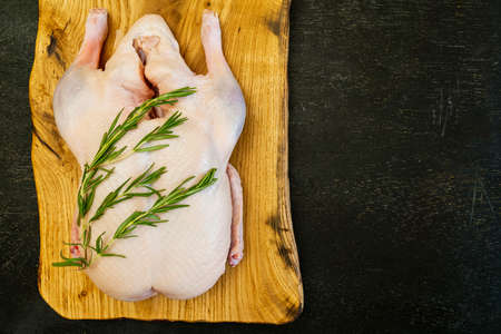 Raw whole duck, spices rosemary on a cutting board handmade oak. Top view. Space for text. Everything you need to make holiday dish. Good quality.の写真素材
