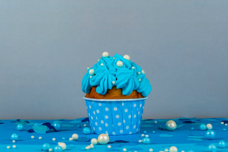 Birthday cupcake with a burning candle, blue background, homemade cakes, ball decorationsの写真素材