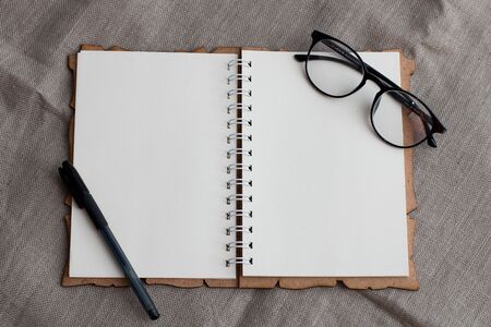 notebook with clean pages on the flax baxkground with glasses on this on and gel pen
