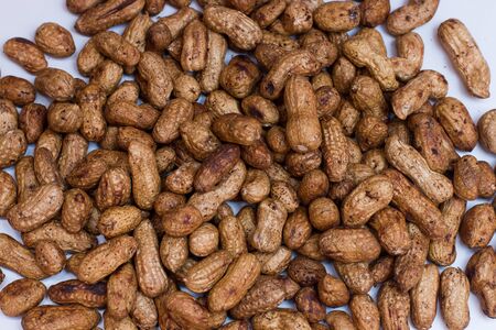 dirty fresh raw nuts arazis on the table are scattered brown white background