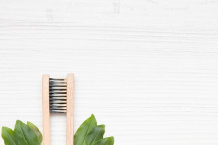 two bamboo toothbrushes connected by bristles on a light wooden background, copy space, green leaves, environmental conservation concept, zero wasteの写真素材