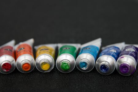 seven tubes of watercolor rainbow colors on a black background copy space blur macroの写真素材