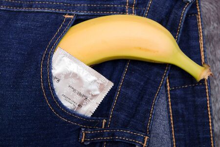 banana and condom sticking out of the back pocket of blue jeans top viewの写真素材