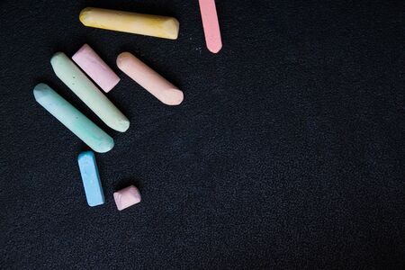 colored crayons on a black background, copy space, top view bright colors contrast