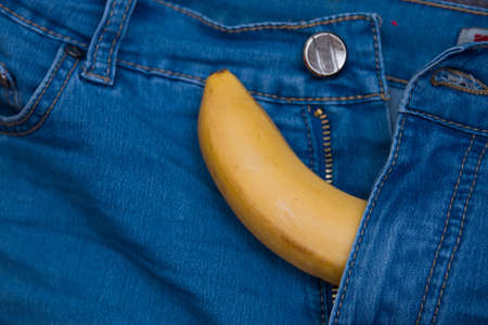 yellow banana sticks out of a zipper blue pants jeans top view copy spaceの写真素材