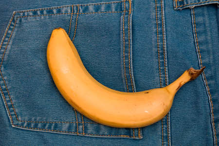 banana lies on the back pocket of blue jeans pants yellow top viewの写真素材