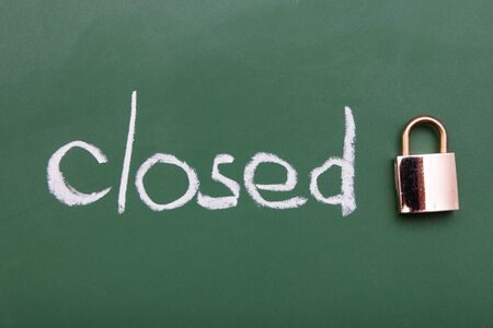 the inscription closed with chalk and padlock on a green blackboard backgroundの写真素材