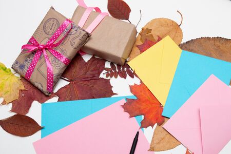 envelopes, cards, thanksgiving gifts, beautiful autumn maple leaves on a white table, copy space. top view, flat lay, ribbons, gift wrapping, send a letterの写真素材
