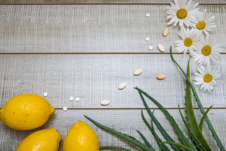 lemons, daisies, aloe leaves and different pills  on a wooden gray background, top view, copy place, hot saleの写真素材