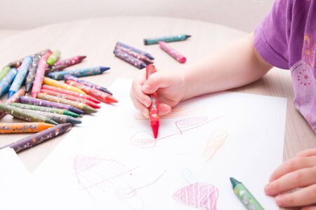 child draws in red colored chalk on paperの写真素材
