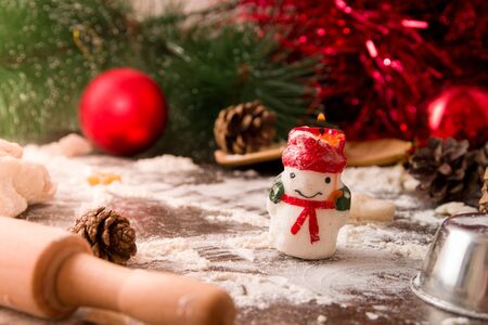 a burning candle in the form of a snowman on the kitchen table, Christmas baking, Christmas decorations, glareの写真素材