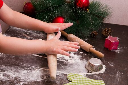 rolling pin child rolls dough for christmas cookies, new year, holiday backgroundの写真素材