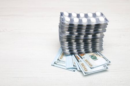 several blisters of tablets on a stack of notes for $ 100, light background, copy spaceの写真素材