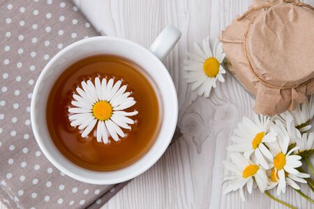 cup of tea and camomile and jar on a polka dot fabric tea can lace grey brown orange beige fliwersの写真素材