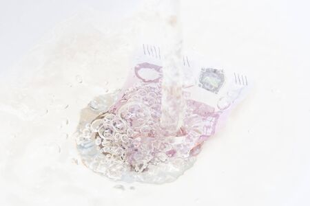 concept of waste of money, overpayments and savings, a 500 euro bill flows away with water in the...