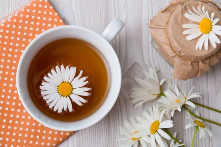 cup of tea and camomile and jar on a polka dot fabric tea can lace grey brown orange beige fliwersの写真素材