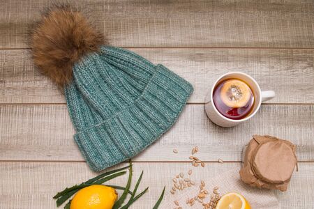 seasonal still life, knitted hat and lemon tea on a wooden table, top viewの写真素材