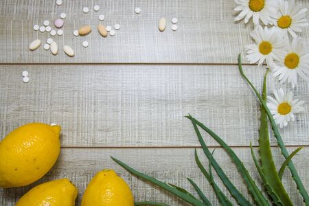 lemons, daisies, aloe leaves and different pills  on a wooden gray background, top view, copy place, hot saleの写真素材