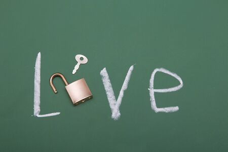 inscription love on a green chalk board, golden padlock with a key instead of the letter o, valentines day conceptの写真素材