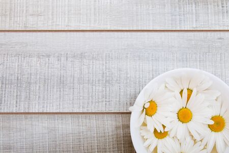 bowl with daisy flowers on a wooden gray table, copy space, top view, white petals of daisiesの写真素材