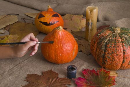children's hand draws with a brush on a pumpkin black paint. preparation for halloween, holiday, atmosphere halloweenの写真素材