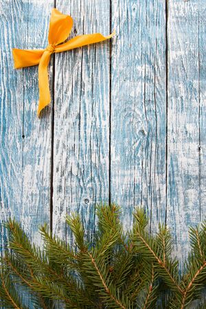 fir branches and golden ribbon bow on a blue wooden background, copy space top viewの写真素材