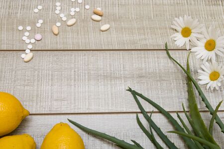 pills, lemons, daisies and aloe leaves on a wooden gray background, top view, copy place, hot saleの写真素材