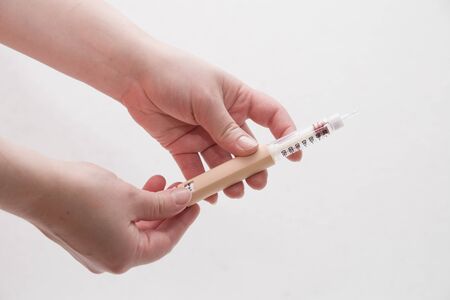 female hands holding a syringe a pen for insulin injection to a patient with diabetes white backgroundの写真素材