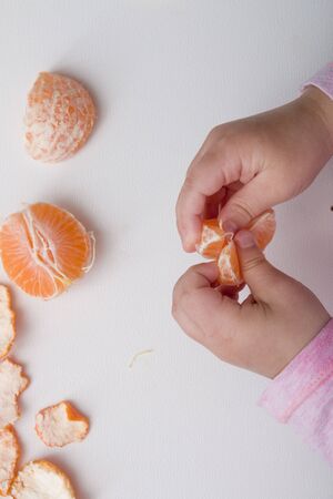 girl\s hand hold a slice of mandarin white background top view orange pinkの写真素材