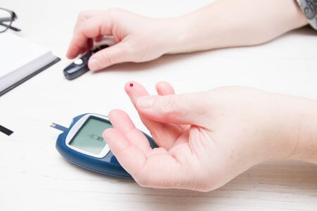 female hand with a drop of blood on a finger, measuring blood sugar, diabetes concept, glucose meter...