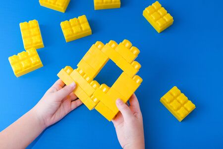 child stands out of yellow constructor house on blue background
