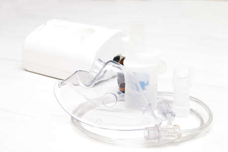 inhaler accessories for him and medicine in a bottle, on the table, a light wooden background with...