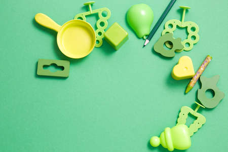 frame made of wooden and plastic toys of different shades of green on a green background, copy space, top view, early development, games with a child concept, toys for the little onesの写真素材
