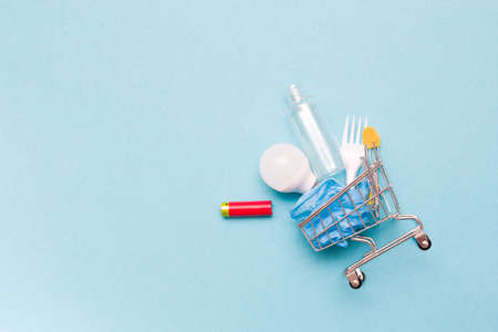 disposable plastic white plug, battery, plastic bag, light bulb and bottle in a shopping trolley on...