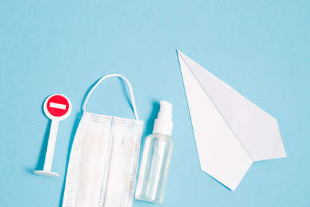 stop sign, alcohol hand antiseptic, protective mask and paper plane on blue background of opium spots top view, quarantine 2020, cancellation of flightsの写真素材