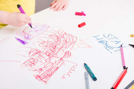 a small child in a yellow T-shirt draws on a large sheet of paper what to do with the child during...