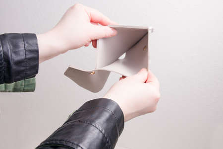 female hands in a jacket open an empty wallet, white background, bankruptcy conceptの写真素材