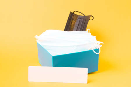 inscription plate and medical face masks in blue box, purple background, copy space, coronavirus concept, donation boxの写真素材