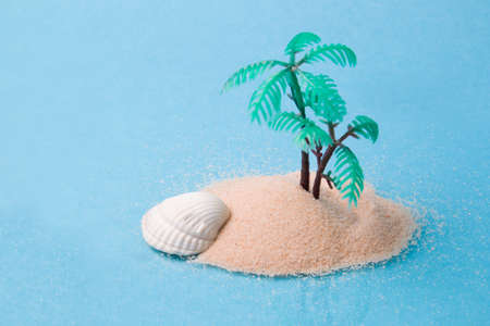 miniature plastic palm tree in the sand, blue background, copy space, reflection in the glass, face...